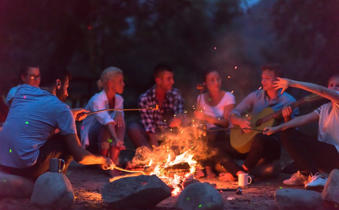 young friends relaxing around campfire